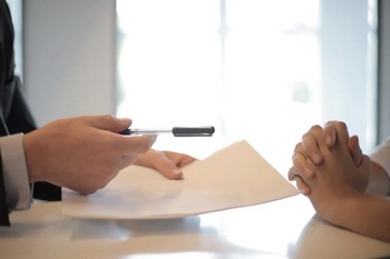 A man and woman collaborate at a table, using a pen and paper for notes.