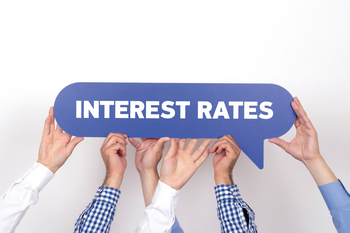 Three people holding a sign over their heads that reads 'interest rates'